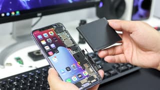 Modern smartphone with removable battery being swapped out, showing the battery compartment and spare battery
