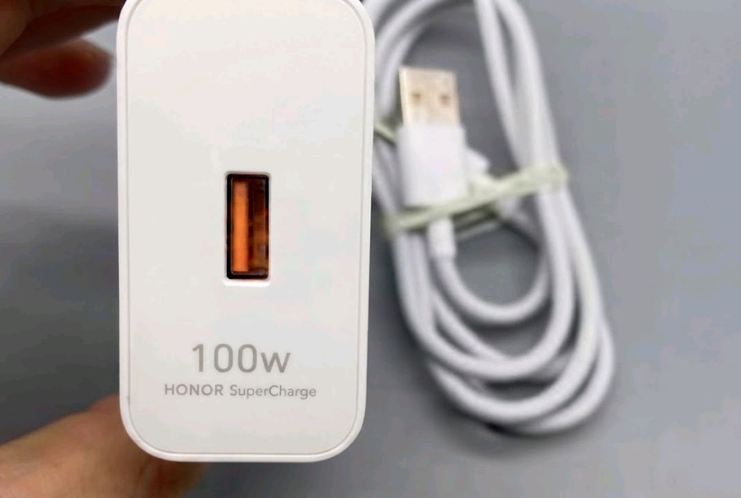 Honor SuperCharge 100W adapter and USB-C cable on a wooden desk