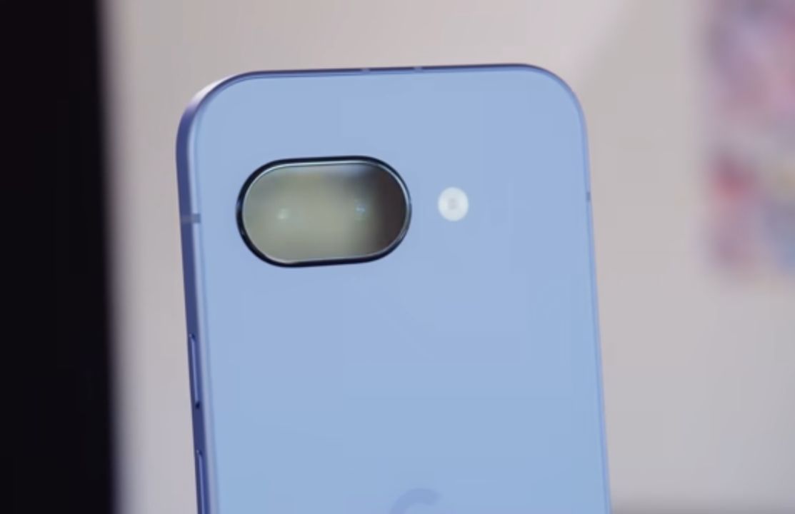 Google Pixel 9a on a desk beside a wireless charging puck