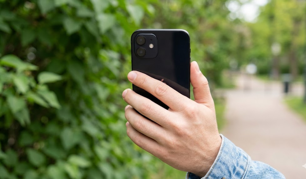iPhone 12 in black color held in hand outdoor natural background