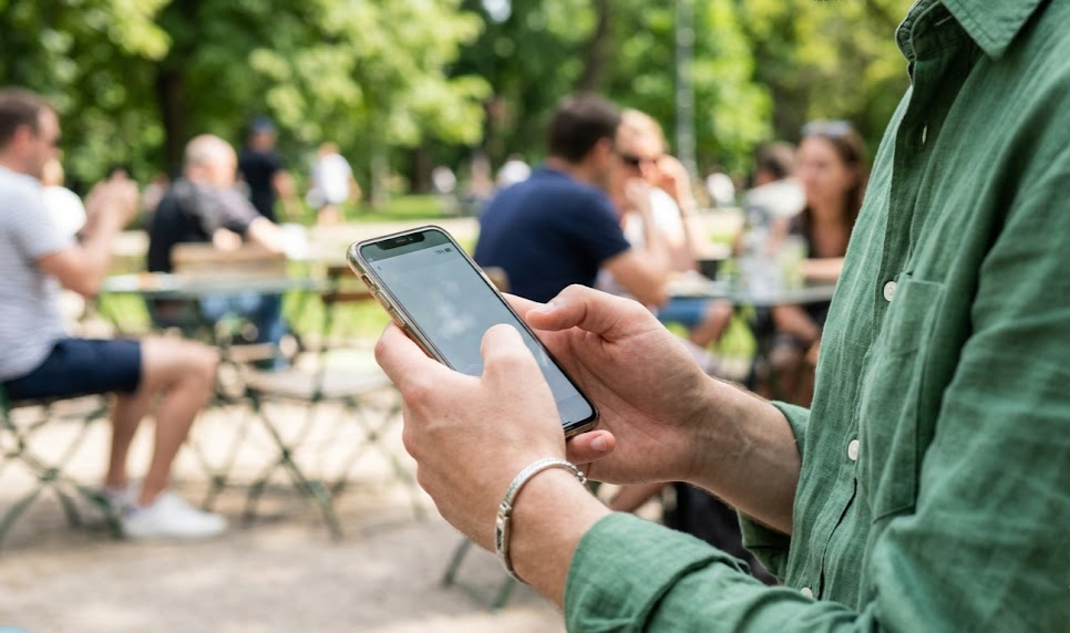 Person using iPhone outdoors in bright sunlight with battery percentage visible