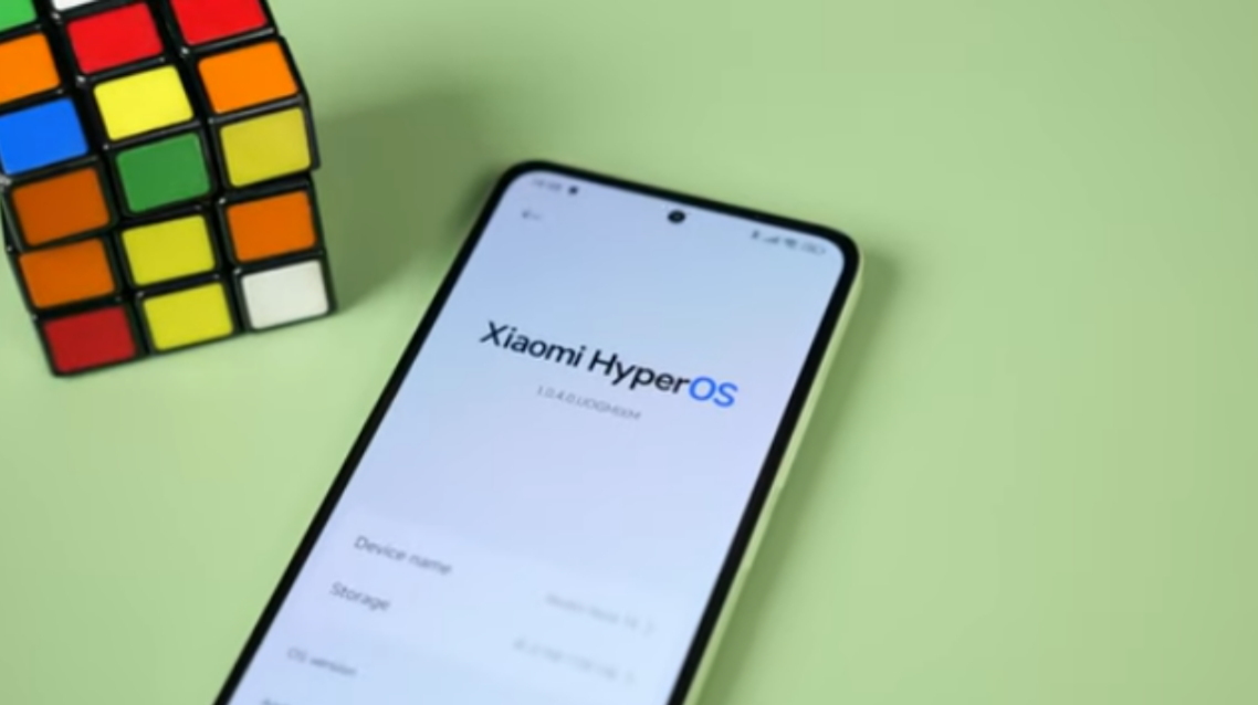 A hand holding the Redmi Note 14 with the MIUI home screen visible — clean on the surface but carrying software baggage underneath