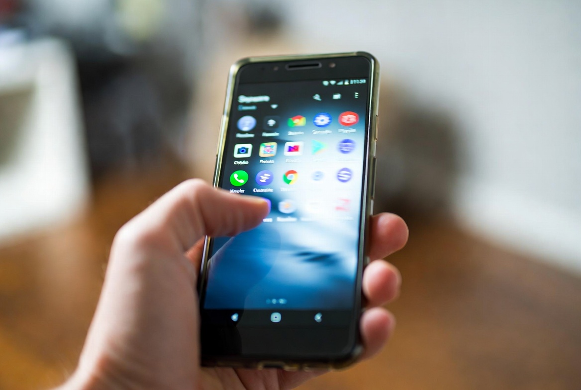 A hand holding an Android phone showing a stuttering app switcher