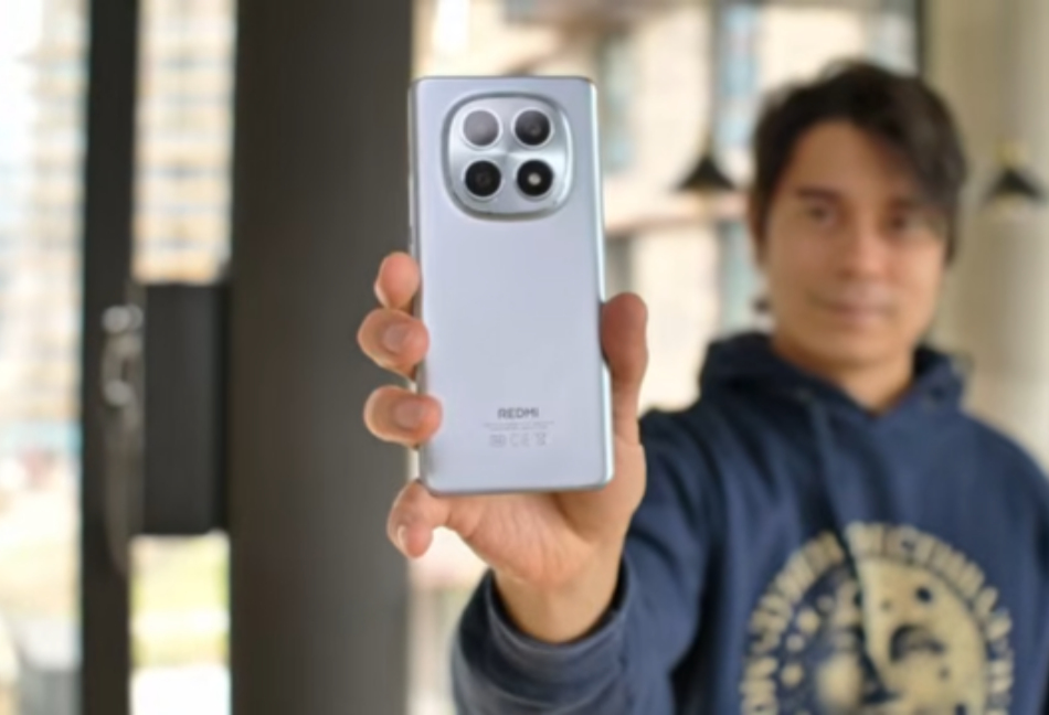 A Xiaomi Redmi Note smartphone laid flat on a clean wooden surface beside a cup of coffee — overhead product shot showing the display and textured back panel clearly against natural light